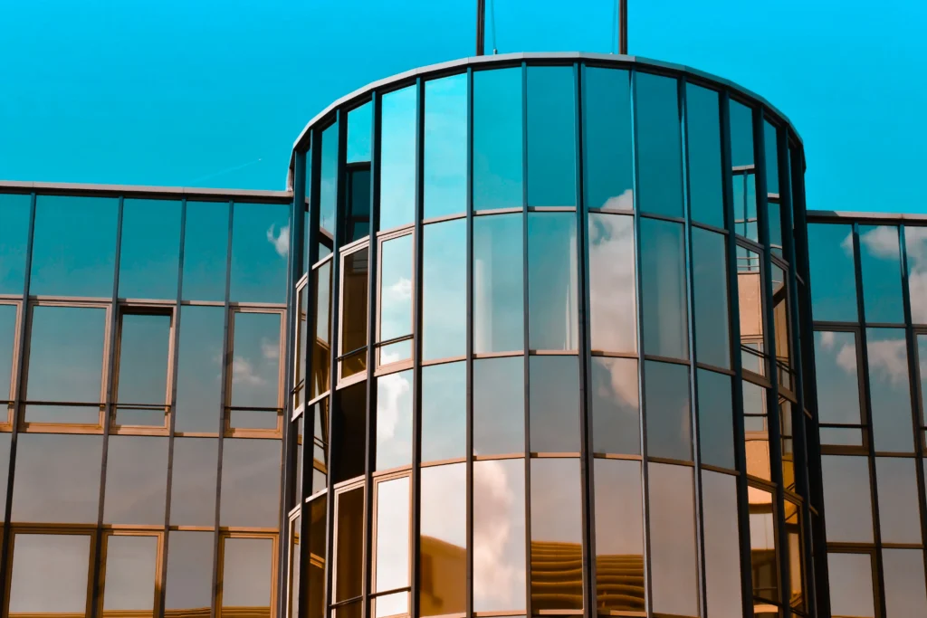 Gedung perkantoran melengkung berpanel kaca reflektif biru yang efisien dan elegan.